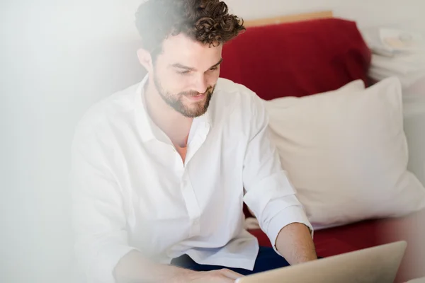 सुंदर हिप्स्टर आधुनिक आदमी लैपटॉप का उपयोग करके घर पर काम कर रहा है — स्टॉक फ़ोटो, इमेज