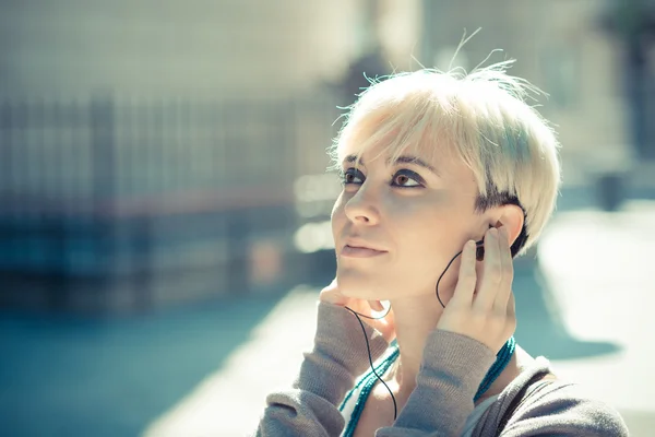 Beautiful young blonde short hair hipster woman listening music — Stock Photo, Image