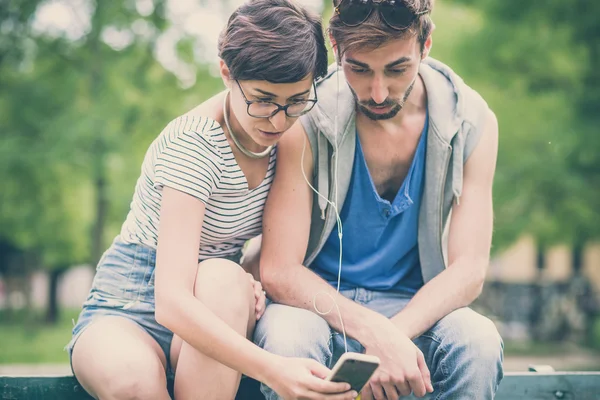 Couple d'amis jeune homme et femme en utilisant smartphone — Photo