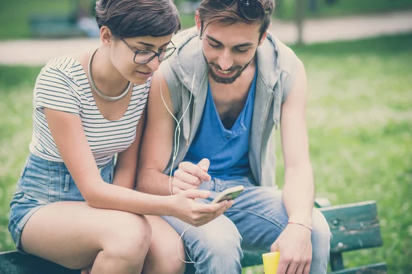 Pareja de amigos joven hombre y mujer usando teléfono inteligente — Foto de Stock