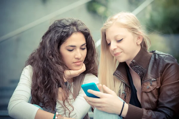 Jovens mulheres elegantes usando telefone inteligente — Fotografia de Stock