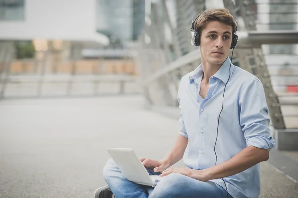 Joven modelo hansome hombre rubio con portátil y auriculares —  Fotos de Stock