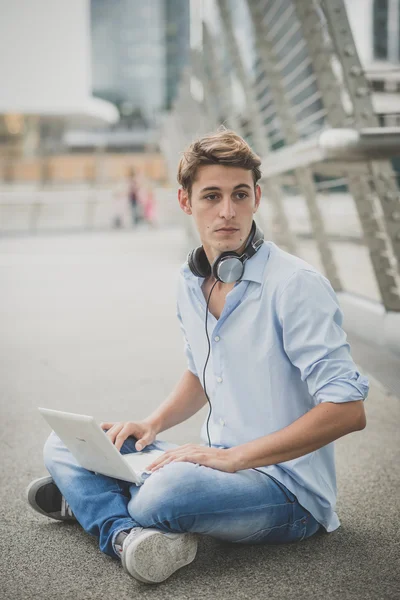 Joven modelo hansome hombre rubio con portátil y auriculares — Foto de Stock