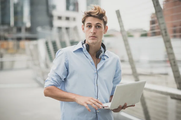 Jovem modelo hansome loiro homem com notebook e fones de ouvido — Fotografia de Stock