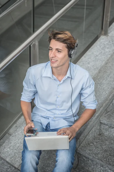 Joven modelo hansome rubia hombre auriculares y portátil —  Fotos de Stock