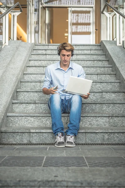 Молодая модель hansome блондин мужчина наушники и ноутбук — стоковое фото