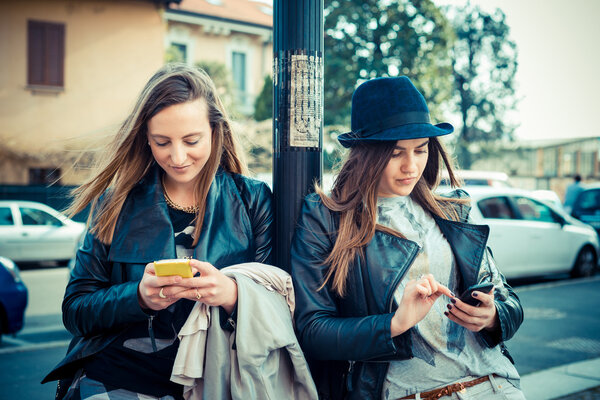 Two beautiful friends using mobile phones