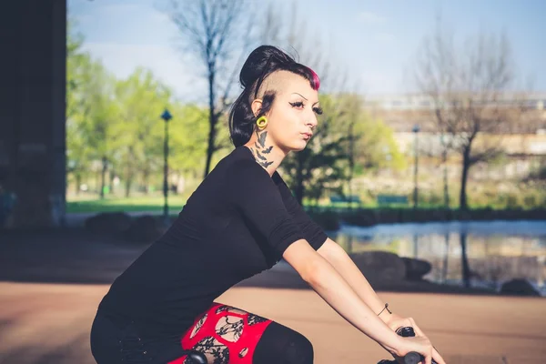 Young beautiful punk dark girl riding bike — Stock Photo, Image