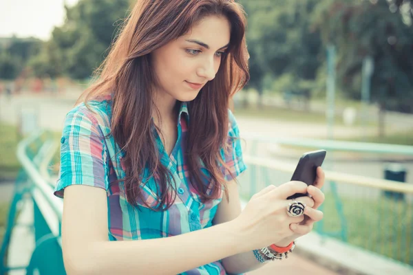 Hermosa joven hipster mujer usando teléfono inteligente — Foto de Stock