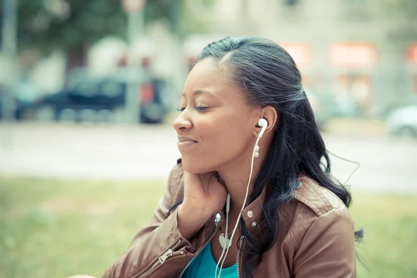 Όμορφη νεαρή αφρικανική γυναίκα που ακούει μουσική ακουστικά — Φωτογραφία Αρχείου