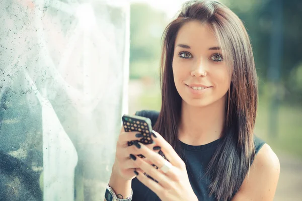 Jonge mooie brunette rechte haren vrouw met behulp van smartphone — Stockfoto