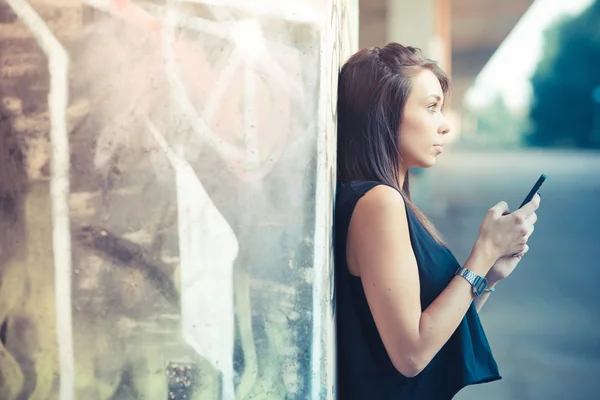 Jonge mooie brunette rechte haren vrouw met behulp van smartphone — Stockfoto