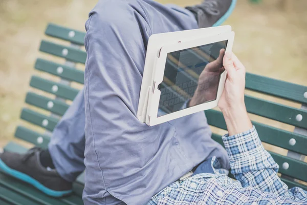 Zblízka do rukou muže pomocí tablet ležící na lavičce — Stock fotografie