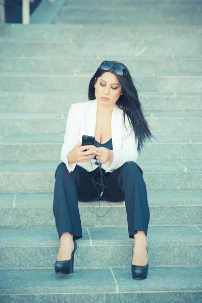 Güzel uzun siyah saçları şık iş kadını smartphon kullanarak — Stok fotoğraf