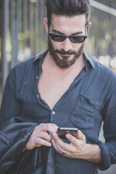 Uomo modello barbuto utilizzando smartphone — Foto Stock