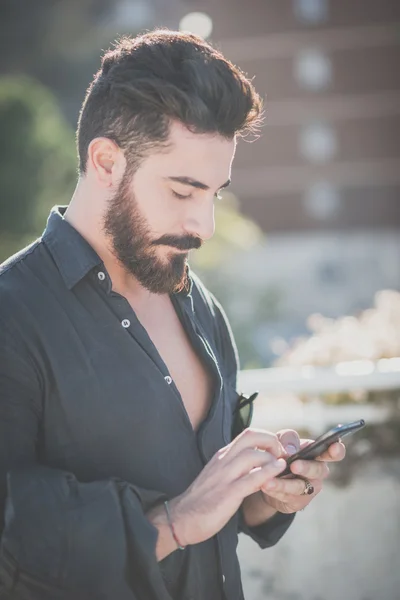 Bebaarde model man met smartphone — Stockfoto