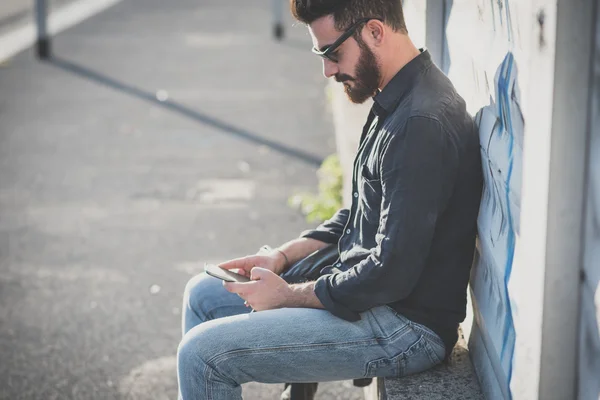 Jovem bonito atraente barbudo modelo homem usando smartphone — Fotografia de Stock