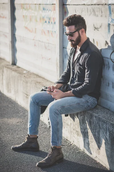 Joven guapo atractivo barbudo modelo hombre usando smartphone — Foto de Stock