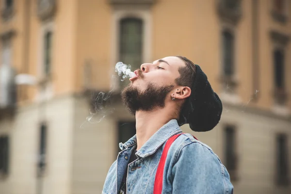 Mladý pohledný vousatých bederní muž kouření cigaret — Stock fotografie