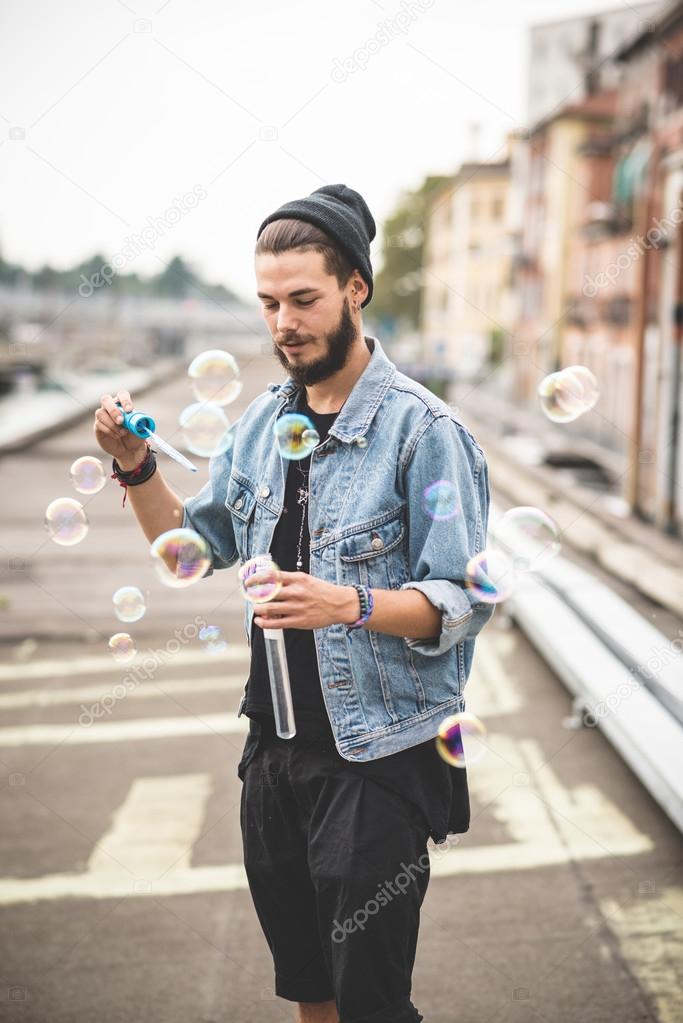 young handsome bearded hipster man blowing bubbles soap