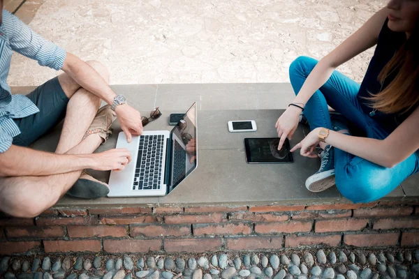 Fiatal pár használ technológia multitasking smarpthone tabletta és — Stock Fotó