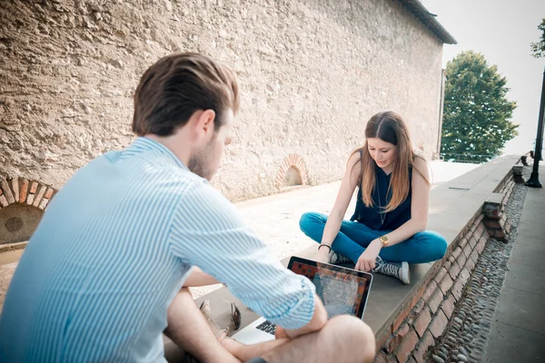 Mladý pár pomocí technologie multitasking smarpthone tabletu a — Stock fotografie