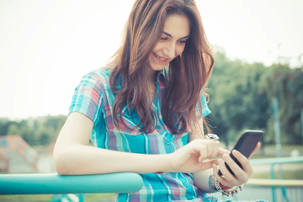 Hermosa joven hipster mujer usando teléfono inteligente — Foto de Stock