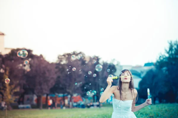 Hermosa joven con vestido blanco soplando burbuja — Foto de Stock