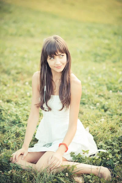 Schöne junge Frau mit weißem Kleid hört Musik — Stockfoto