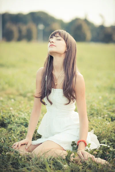 Schöne junge Frau mit weißem Kleid hört Musik — Stockfoto