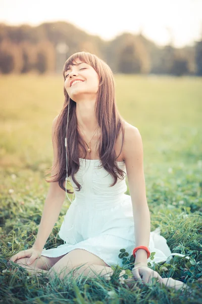 白いドレスの音楽を聴きながら美しい若い女性 — ストック写真