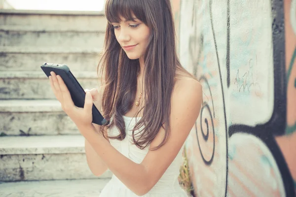 Belle jeune femme avec robe blanche en utilisant une tablette — Photo