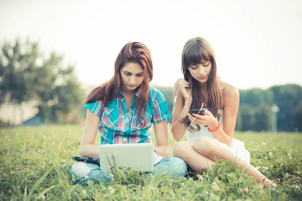 Irmãs usando tablet e smartphone no parque — Fotografia de Stock