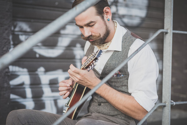handsome big moustache hipster man playing mandolin