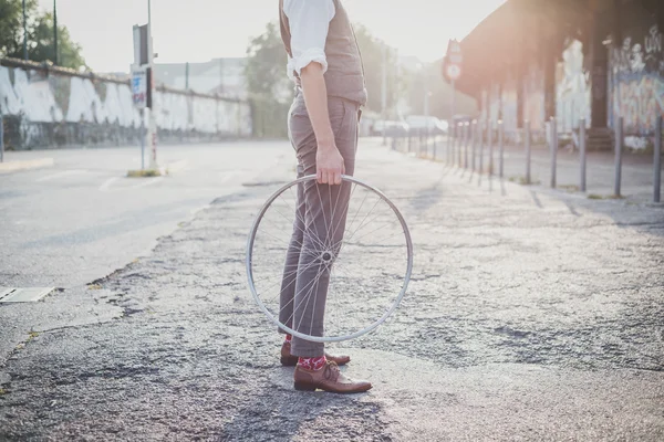 Κοντινό πλάνο πόδια παπούτσια hipster άνθρωπος που κρατά την παλιά ρόδα ποδηλάτων — Φωτογραφία Αρχείου