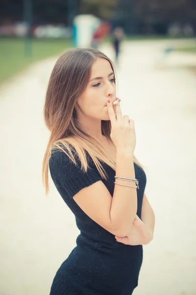 Ung kvinna med cigarett utomhus — Stockfoto