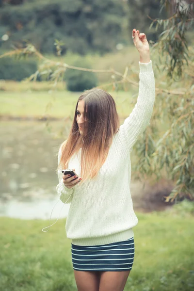 Ung kvinna lyssnar musik i parken — Stockfoto