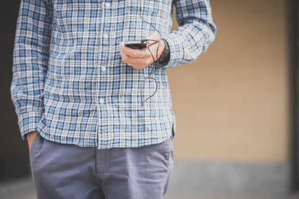 Hombre casual escuchando música y usando smartphone — Foto de Stock