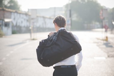 Sarışın adam sokakta yürürken bir çanta