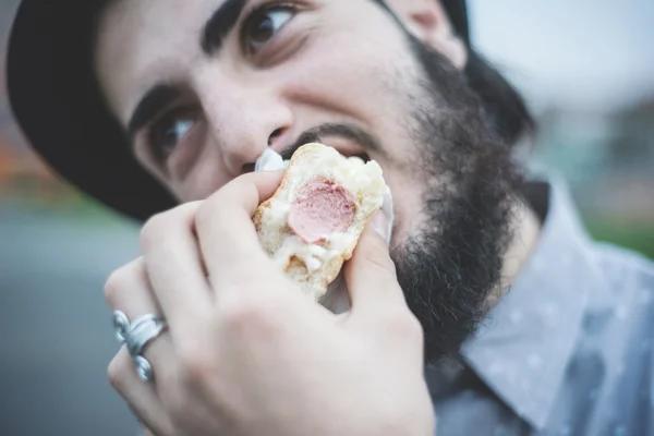 Hipster muže jíst hot dog — Stock fotografie