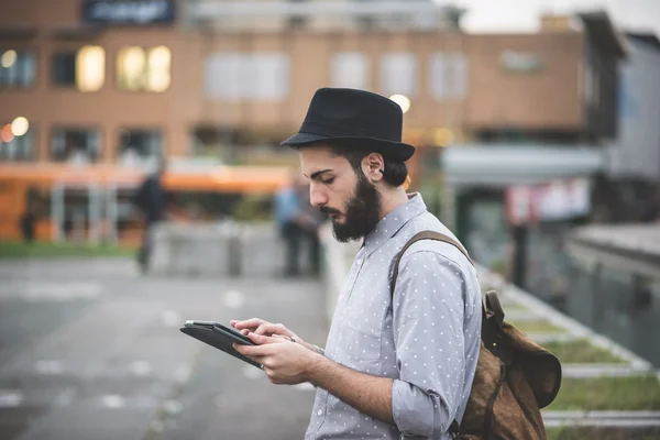 Hipster gay no chapéu usando tablet digital — Fotografia de Stock