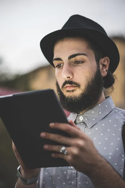 Hipster gay in cappello utilizzando digitale tablet — Foto Stock
