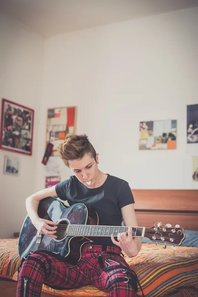 Jovem lésbica elegante cabelo estilo mulher tocando guitarra — Fotografia de Stock