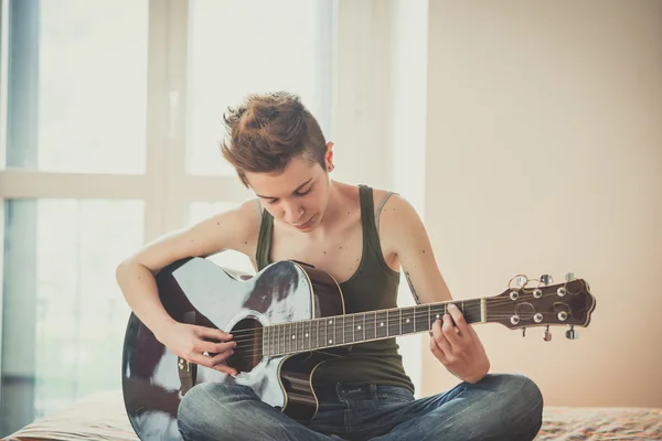 Jonge lesbische stijlvolle haren stijl vrouw gitaarspelen — Stockfoto