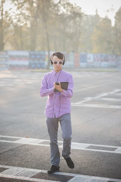 Jovem na cidade com tablet e fones de ouvido — Fotografia de Stock