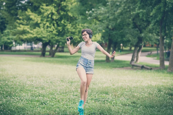 Jonge hipster vrouw luisteren naar muziek springen — Stockfoto