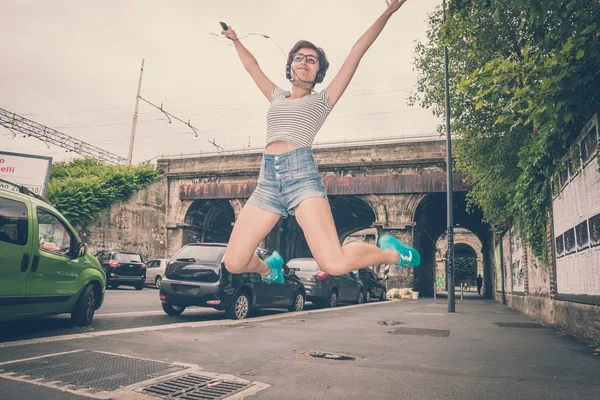 ジャンプの音楽を聴く若い流行に敏感な女性 — ストック写真