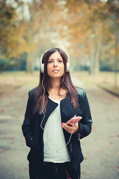 Молодая девушка в парке слушает музыку — стоковое фото