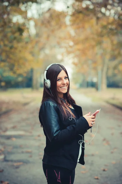 Ung flicka i parken lyssnar musik — Stockfoto