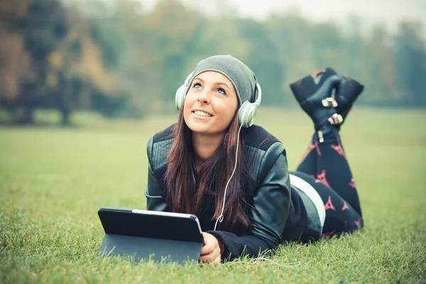 Chica joven en el parque escuchando música — Foto de Stock